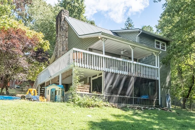 back of house with a wooden deck, a yard, a chimney, stairs, and metal roof