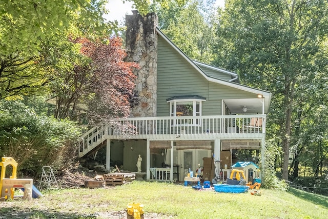 rear view of property with a deck, a playground, a yard, stairway, and a chimney