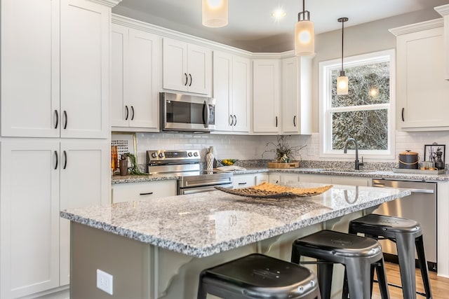 kitchen featuring a kitchen island, a sink, decorative backsplash, stainless steel appliances, and a kitchen bar