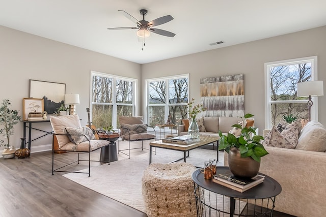 living area featuring ceiling fan, visible vents, baseboards, and wood finished floors