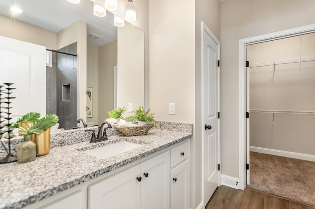 bathroom featuring a spacious closet, visible vents, baseboards, wood finished floors, and vanity