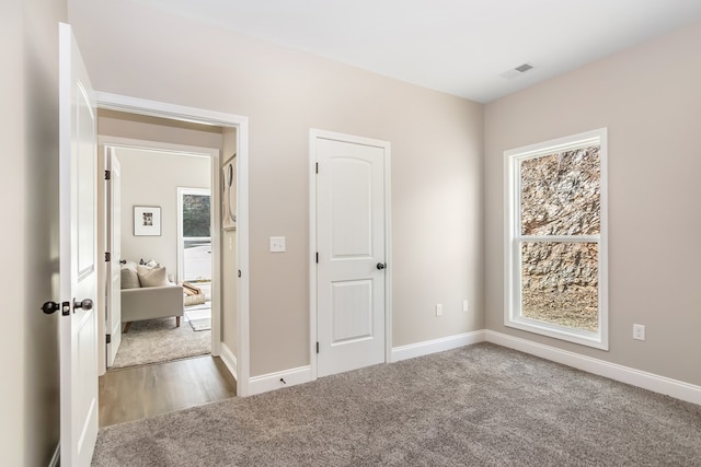 unfurnished bedroom with carpet flooring, visible vents, and baseboards