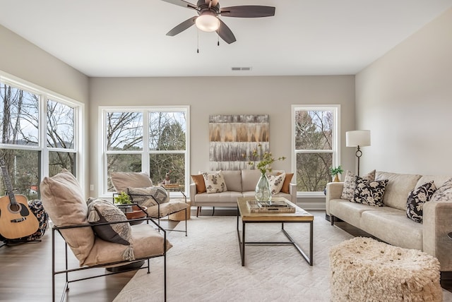 living room with light wood-type flooring, visible vents, and ceiling fan