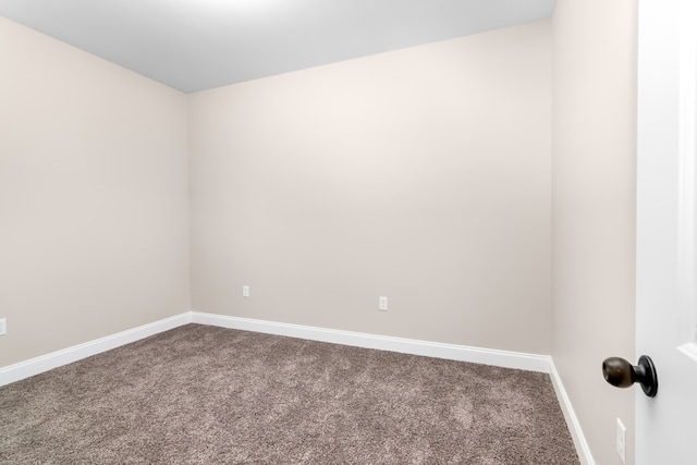 unfurnished room featuring baseboards and dark colored carpet