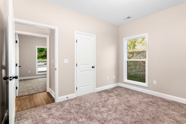 unfurnished bedroom with visible vents, carpet, and baseboards