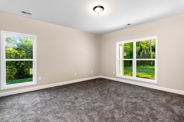 unfurnished room featuring baseboards, visible vents, and dark carpet