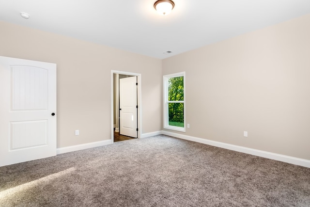 unfurnished bedroom featuring dark colored carpet, visible vents, and baseboards