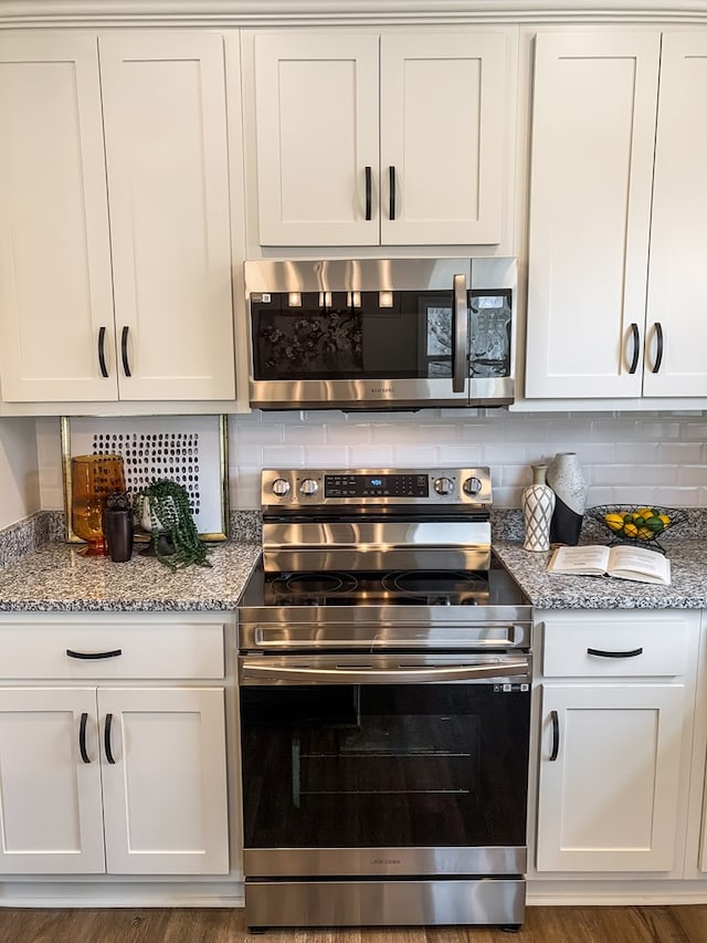 kitchen featuring white cabinetry, light stone countertops, backsplash, and stainless steel appliances