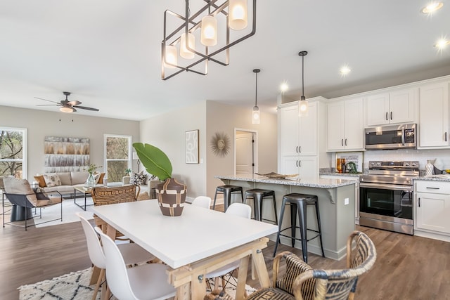 kitchen featuring a kitchen island, dark wood finished floors, a breakfast bar, appliances with stainless steel finishes, and white cabinets