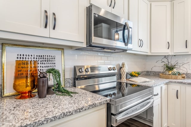 kitchen featuring light stone counters, decorative backsplash, white cabinetry, and stainless steel appliances