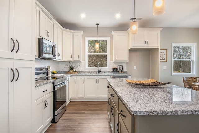 kitchen with a sink, decorative light fixtures, tasteful backsplash, a kitchen island, and stainless steel appliances