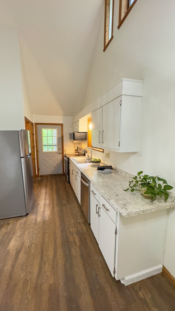 kitchen with high vaulted ceiling, white cabinetry, appliances with stainless steel finishes, and dark wood-type flooring