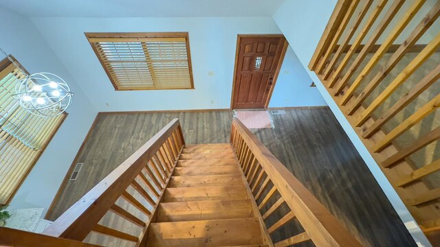 stairway with wood-type flooring and a notable chandelier