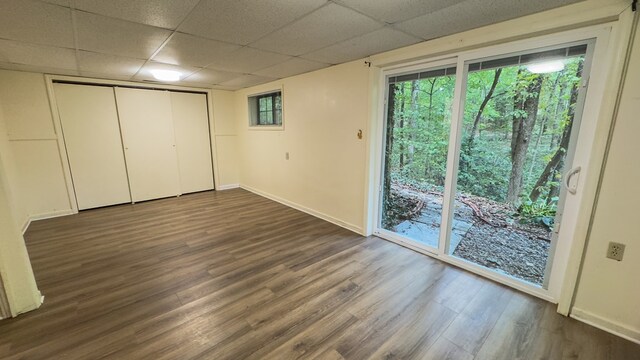 unfurnished bedroom with access to outside, a drop ceiling, dark hardwood / wood-style floors, and a closet