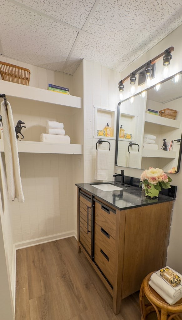 bathroom with wood-type flooring, vanity, and a paneled ceiling