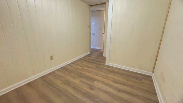 empty room with wood-type flooring and wooden walls