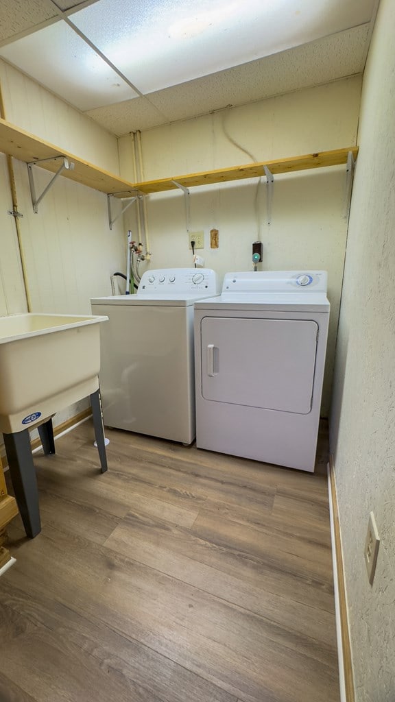 washroom with washing machine and clothes dryer and hardwood / wood-style floors