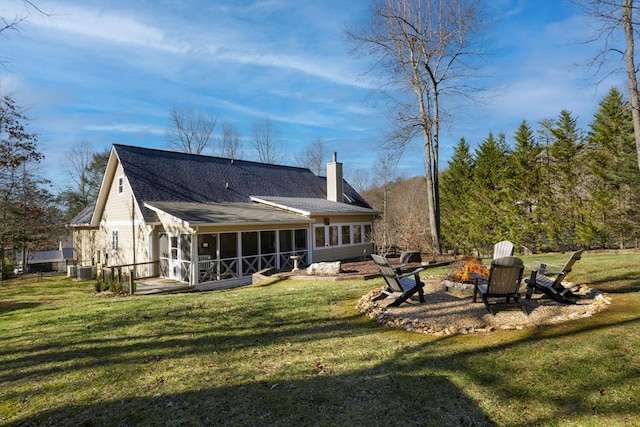 rear view of house featuring a sunroom, a yard, and an outdoor fire pit