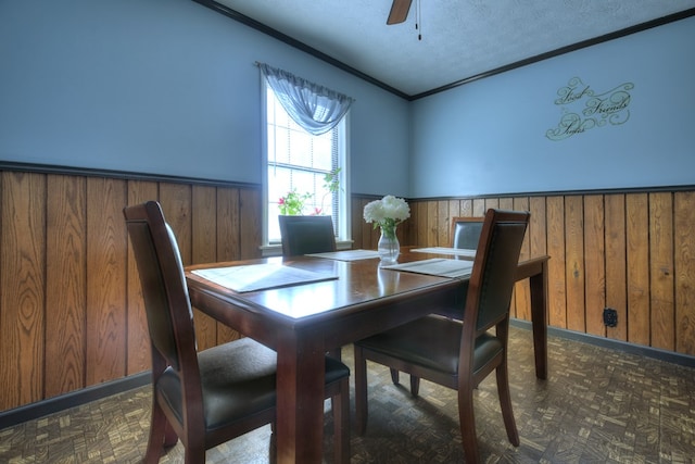 dining space with dark parquet flooring, wooden walls, ornamental molding, and a textured ceiling