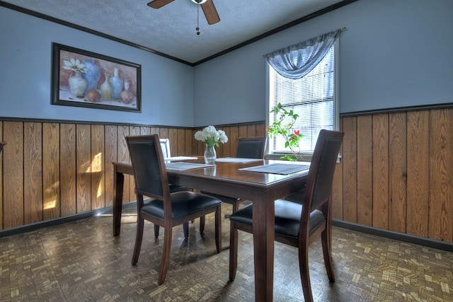 dining area with wooden walls, dark parquet floors, ceiling fan, crown molding, and a textured ceiling