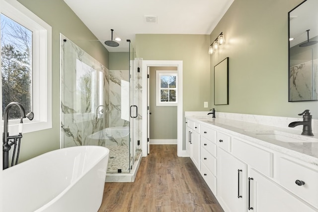 full bathroom featuring a freestanding tub, a marble finish shower, a sink, and wood finished floors