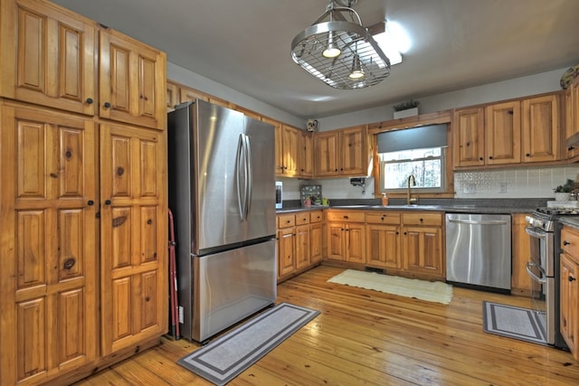 kitchen featuring light wood-type flooring, appliances with stainless steel finishes, backsplash, and sink