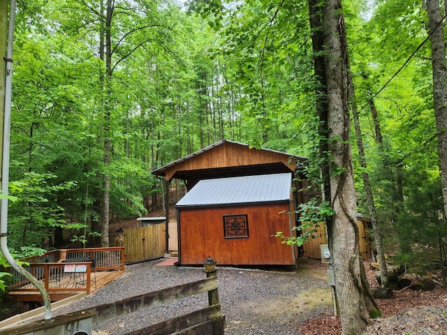 view of outdoor structure featuring a wooded view and an outbuilding