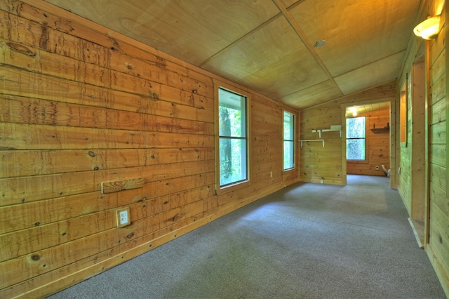 carpeted spare room featuring vaulted ceiling, wooden walls, and wooden ceiling