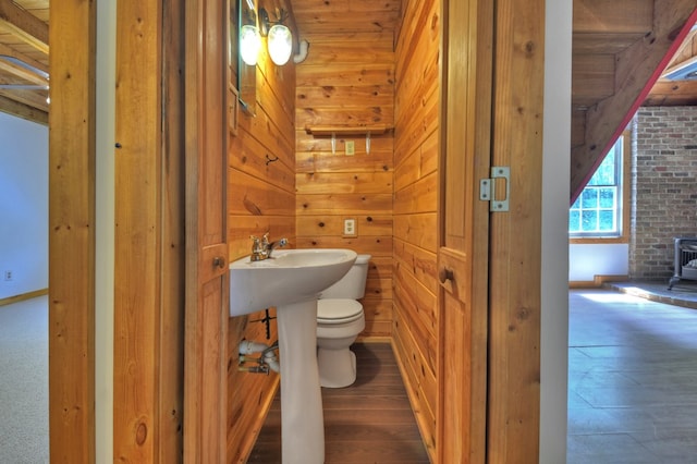bathroom featuring a wood stove, toilet, wooden walls, and wood finished floors