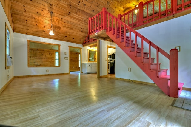 unfurnished living room with high vaulted ceiling, wood finished floors, baseboards, stairs, and wood ceiling