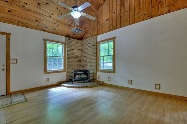 unfurnished living room with wood finished floors, a wood stove, a ceiling fan, high vaulted ceiling, and baseboards