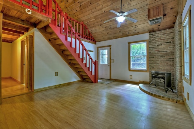 unfurnished living room with wooden ceiling, stairway, baseboards, a wood stove, and wood finished floors