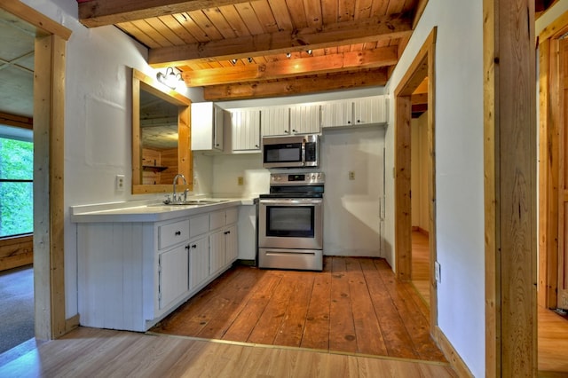 kitchen featuring appliances with stainless steel finishes, a sink, light wood-style flooring, wooden ceiling with exposed beams, and light countertops