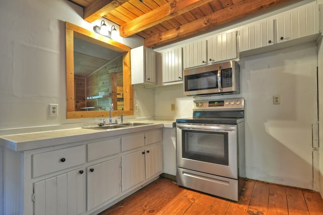 kitchen with stainless steel appliances, a sink, wood ceiling with exposed beams, and hardwood / wood-style flooring
