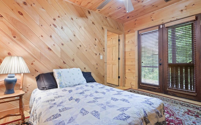 bedroom with ceiling fan, wooden ceiling, multiple windows, and wood walls