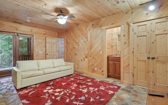 living room featuring wood ceiling, a wealth of natural light, ceiling fan, and wood walls