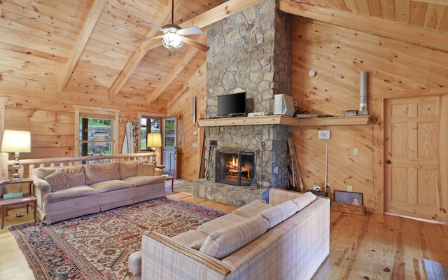 living room with beam ceiling, light hardwood / wood-style flooring, wooden ceiling, wooden walls, and a fireplace