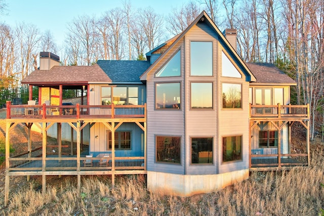 rear view of house featuring a chimney and a shingled roof