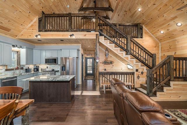 kitchen featuring light stone countertops, dark hardwood / wood-style flooring, wood walls, a kitchen island, and appliances with stainless steel finishes