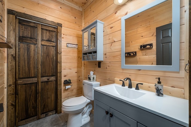 bathroom with vanity, toilet, and wooden walls