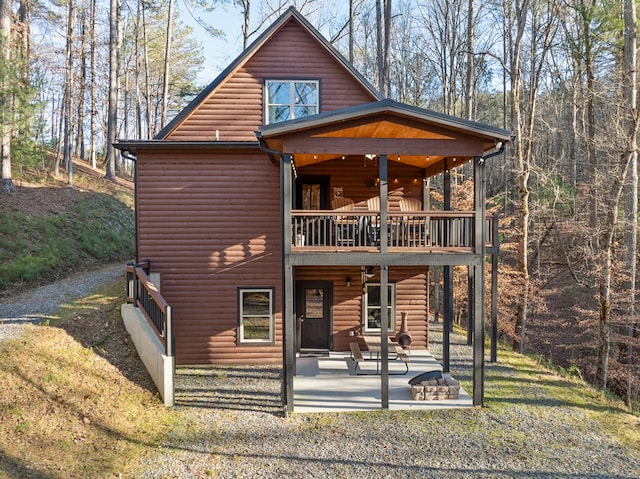 rear view of house with a lawn, a balcony, and a patio