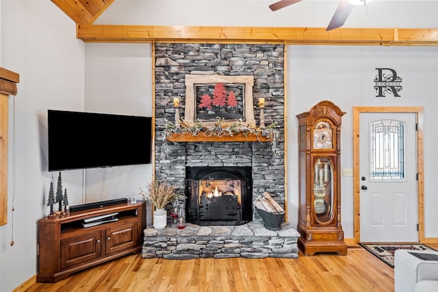 living room with wood-type flooring, lofted ceiling, ceiling fan, and a fireplace