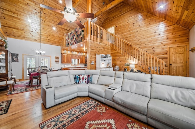 living room with high vaulted ceiling, ceiling fan with notable chandelier, light wood-type flooring, wooden ceiling, and wood walls