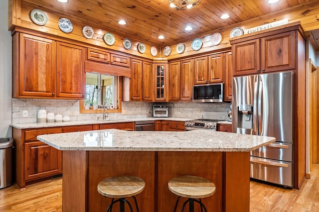 kitchen with a kitchen island, a breakfast bar area, wood ceiling, light stone counters, and stainless steel appliances