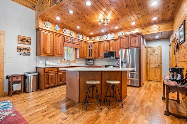 kitchen with light stone counters, wooden ceiling, a kitchen island, stainless steel appliances, and backsplash