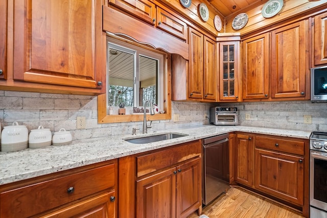 kitchen featuring sink, light hardwood / wood-style flooring, appliances with stainless steel finishes, backsplash, and light stone countertops