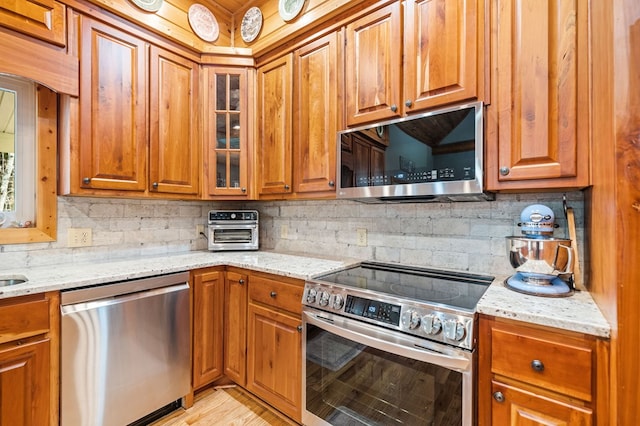 kitchen featuring light stone countertops, appliances with stainless steel finishes, and decorative backsplash