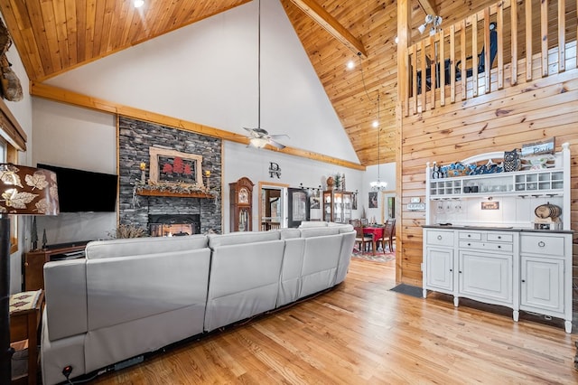 living room featuring a stone fireplace, wooden ceiling, light hardwood / wood-style floors, and ceiling fan