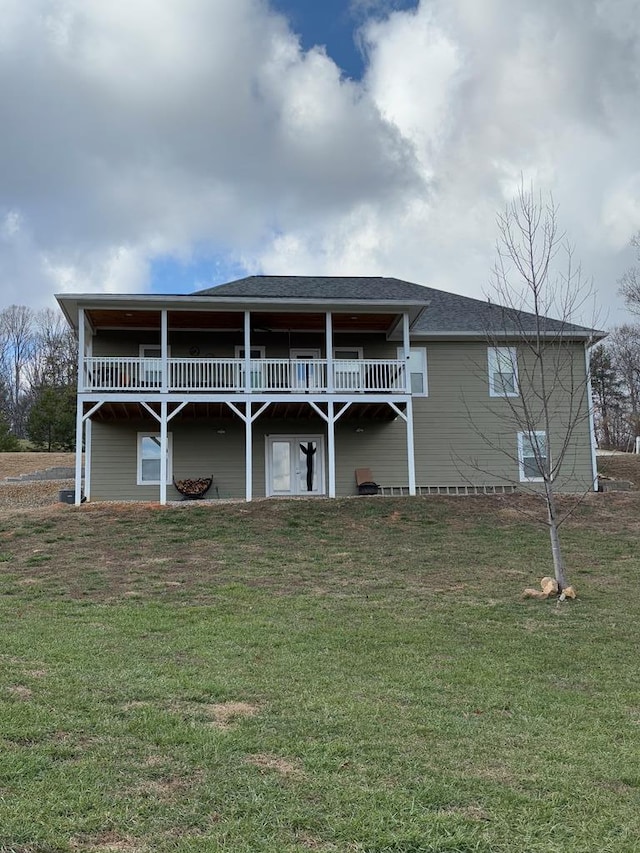 rear view of house featuring a yard, a shingled roof, and a wooden deck