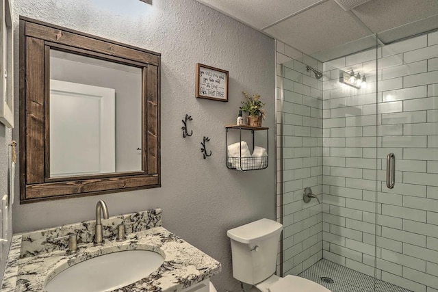 bathroom featuring vanity, toilet, an enclosed shower, and a drop ceiling